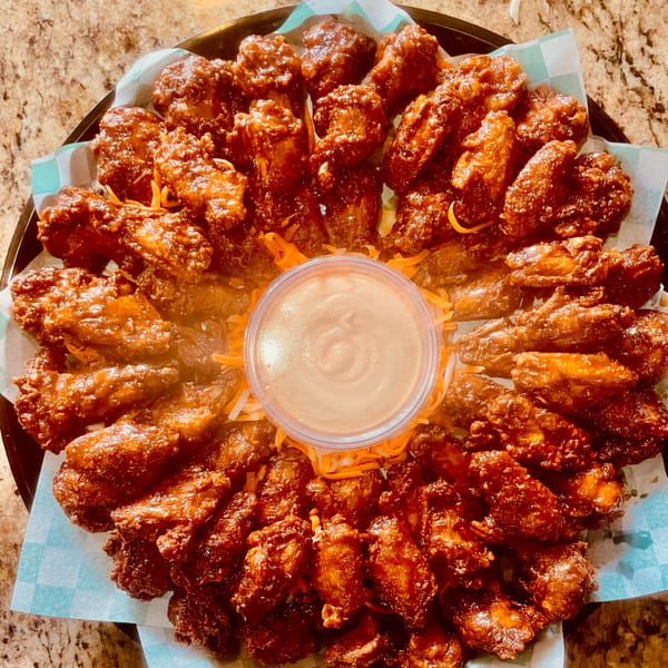 A platter of vPho's Vietnamese-style chicken wings with a dipping sauce in the center.