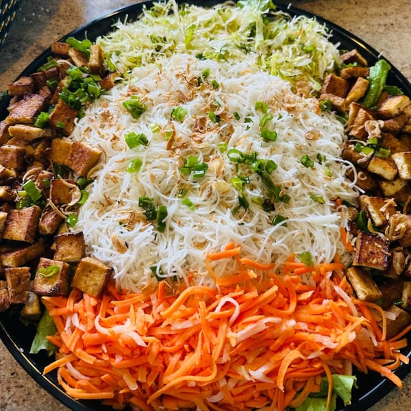 A large platter of Vietnamese vermicelli noodles, tofu, shredded carrots, and cabbage.