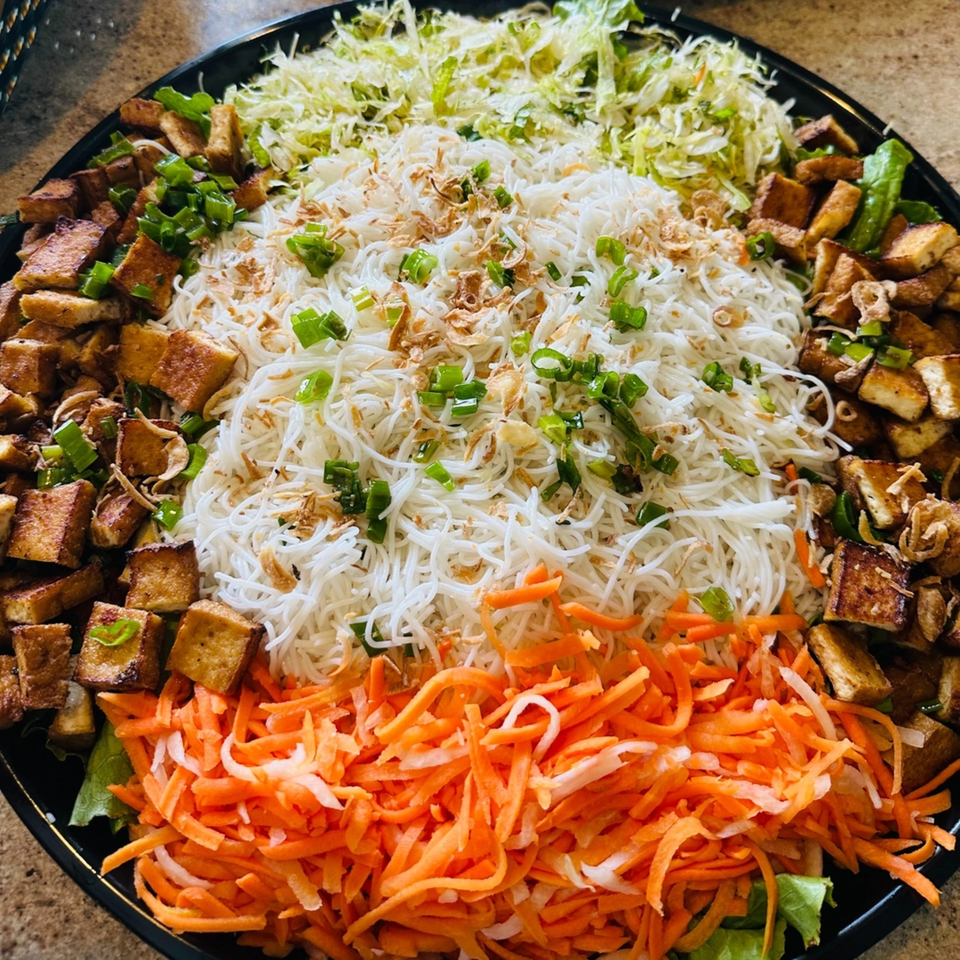 A large platter of Vietnamese vermicelli noodles, tofu, shredded carrots, and cabbage.