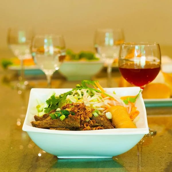 Vietnamese beef and vegetable dish with a spring roll, garnished with fried onions and scallions.