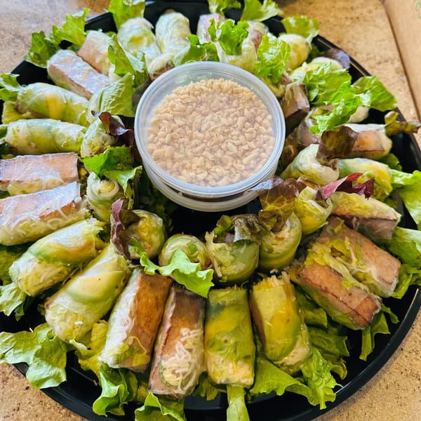 A platter of vPho Vietnamese spring rolls and summer rolls with a peanut dipping sauce.